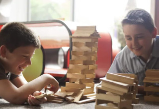 Dos niños juegan felices con bloques de madera en una tienda tipo safari del Resort «Beachside 5» en Bélgica.