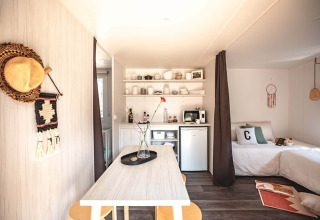 Interior luminoso y acogedor de la tienda safari Resort Beachside 5 en Bélgica, con cocina y zona de cama.