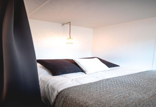 Interior de una tienda safari en Resort Beachside 5, Bélgica, con cama cómoda y luz ambiental cálida.