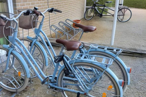 Bicicletas azul claro con cestas están aparcadas cerca de una pared de ladrillo en el Resort Beachside 5 en Bélgica.