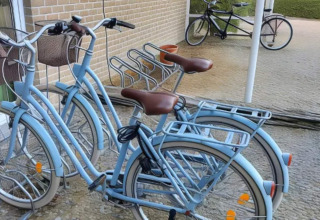 Bicicletas azul claro con cestas están aparcadas cerca de una pared de ladrillo en el Resort Beachside 5 en Bélgica.