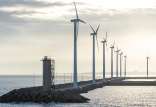 Aerogeneradores alineados cerca del mar en Bélgica vistos desde el Resort «Beachside 5» con faro y costa