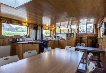 Cucina moderna e luminosa con zona pranzo sulla houseboat St Antoine Isera in Belgio con interni in legno.