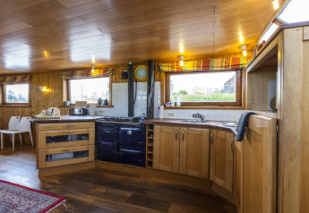 Cucina accogliente con interni in legno e grandi finestre nella houseboat St Antoine Isera in Belgio.