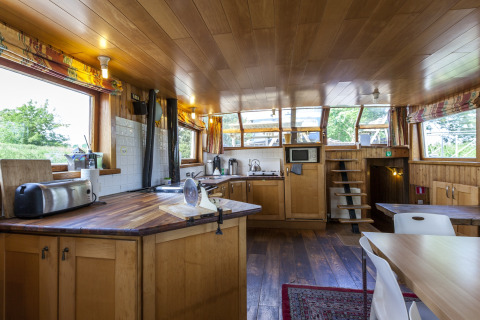 Moderne køkken og spiseområde ombord på husbåden St Antoine Isera i Belgien, med lyse træmøbler.