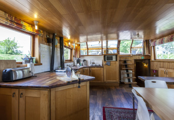 Cucina luminosa e zona pranzo sulla houseboat St Antoine Isera in Belgio, con arredamento in legno chiaro.