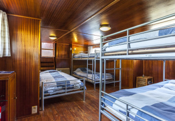 Dormitorio sulla houseboat St Antoine Isera in Belgio con letti a castello e rivestimenti in legno.