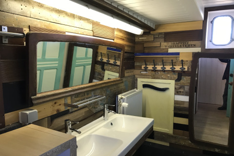 Badeværelse på husbåden St Antoine Isera i Belgien med dobbeltspejle, vaske og unikt trædesign.
