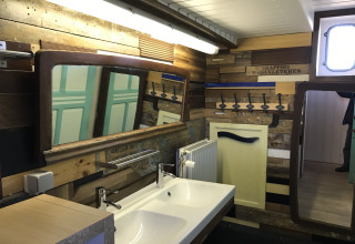 Badeværelse på husbåden St Antoine Isera i Belgien med dobbeltspejle, vaske og unikt trædesign.