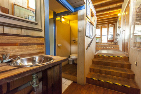Indvendig udsigt over husbåd St Antoine Isera i Belgien med et toilet, håndvask og trætrappe.