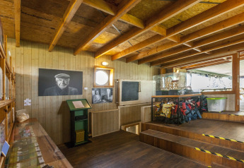 Interno della houseboat 'St Antoine Isera' in Belgio con pannelli in legno, foto e giubbotti di salvataggio.