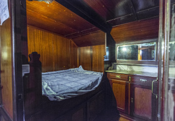 Zona notte con pannelli in legno e mobili a bordo della houseboat St Antoine Isera in Belgio.
