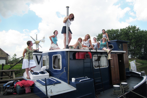 Eine Gruppe von Frauen sitzt und steht auf dem Hausboot St Antoine in Belgien an einem sonnigen Tag.