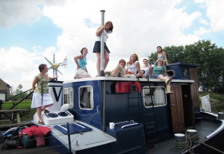 Eine Gruppe von Frauen sitzt und steht auf dem Hausboot St Antoine in Belgien an einem sonnigen Tag.