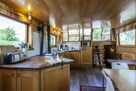 Küche und Essbereich auf dem Hausboot St Antoine in Belgien, mit Holzdekor und großen Fenstern.