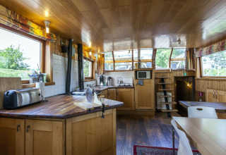 Küche und Essbereich auf dem Hausboot St Antoine in Belgien, mit Holzdekor und großen Fenstern.