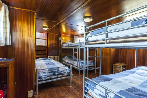 Innenansicht eines Schlafsaals mit Etagenbetten und Holzverkleidung auf dem Hausboot St Antoine in Belgien.