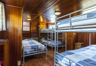Innenansicht eines Schlafsaals mit Etagenbetten und Holzverkleidung auf dem Hausboot St Antoine in Belgien.