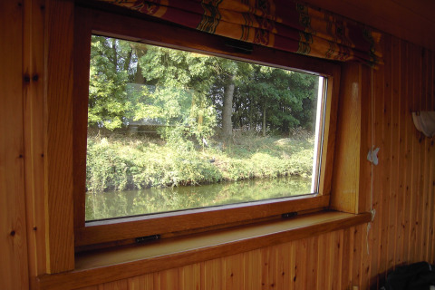 Blick aus dem Fenster des Hausboots 'St Antoine' in Belgien, mit Holzverkleidung und Naturblick.