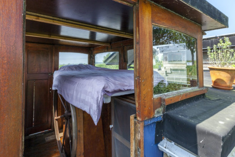 Bett mit lila Bettwäsche befindet sich am Steuerrad der Hausboot 'St Antoine' in Belgien, mit Ausblick.