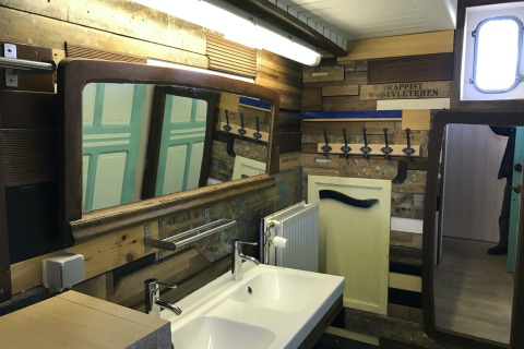 Badezimmer auf dem Hausboot 'St Antoine' in Belgien mit Holzwänden, großen Spiegeln und Doppelwaschbecken.
