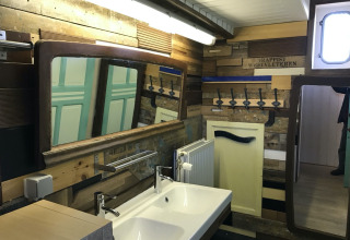 Badezimmer auf dem Hausboot 'St Antoine' in Belgien mit Holzwänden, großen Spiegeln und Doppelwaschbecken.