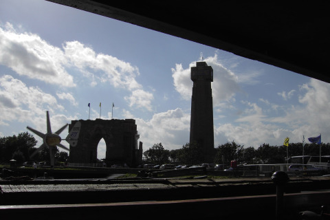 Blick von Hausboot «St Antoine» in Belgien auf ein historisches Tor und einen Turm bei Tageslicht.