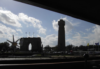 Udsigt fra husbåd «St Antoine» i Belgien med en historisk bygning og tårn silhouetteret mod himlen.