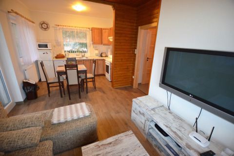 Soggiorno e cucina dello chalet Marcela in Repubblica Ceca con tavolo da pranzo, divano e TV.