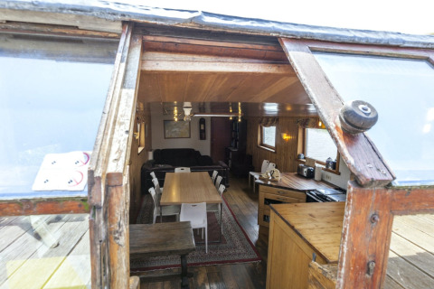 Blick in das Wohnzimmer des Hausboots St Antoine in Belgien mit Holzausstattung und Esstisch.