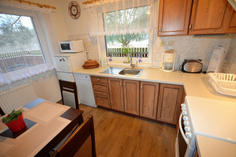 Accogliente cucina nello chalet Marcela in Repubblica Ceca con mobili in legno, elettrodomestici e tavolo.