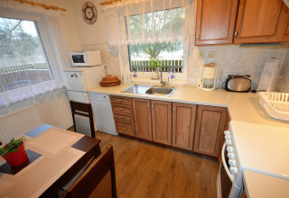 Accogliente cucina nello chalet Marcela in Repubblica Ceca con mobili in legno, elettrodomestici e tavolo.