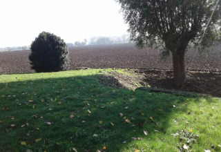 Blick von Hausboot St Antoine in Belgien auf eine grüne Wiese, Bäume und ein gepflügtes Feld.
