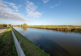Blick von dem Hausboot 'St Antoine' in Belgien, mit einem ruhigen Kanal, Wiesen und blauem Himmel.