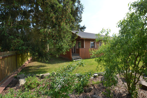 Chalet Marcela in Repubblica Ceca, circondato da un giardino verde e alberi in una giornata di sole.
