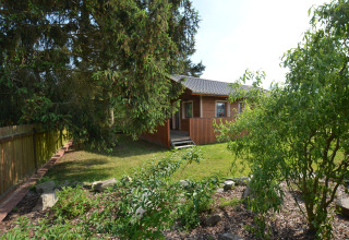 Chalet Marcela in Repubblica Ceca, circondato da un giardino verde e alberi in una giornata di sole.