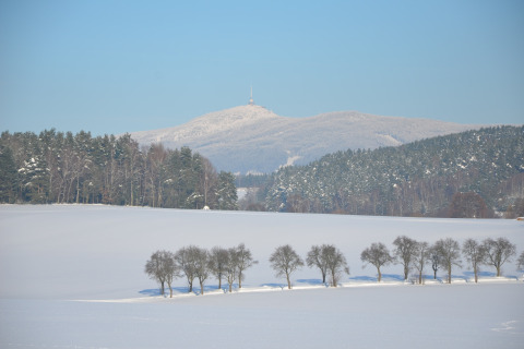 Paesaggio invernale dal chalet Marcela nella Repubblica Ceca con campo innevato, alberi e montagne lontane.