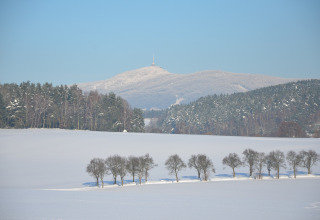 Paesaggio invernale dal chalet Marcela nella Repubblica Ceca con campo innevato, alberi e montagne lontane.