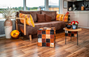 Salon moderne du Houseboat am Bärwalder See avec canapé marron, coussins colorés et sol en bois chaud.