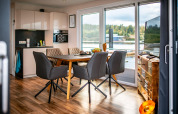Intérieur d'une péniche moderne avec cuisine, salle à manger et grandes fenêtres donnant sur le Bärwalder See.