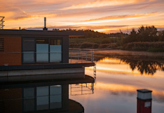 Houseboat am Bärwalder See galleggia sull’acqua tranquilla al tramonto riflettendo il cielo colorato.