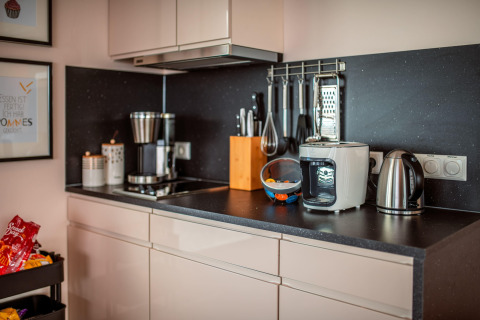 Modern kitchen counter featuring a coffee maker, kettle, air fryer, and utensils on Houseboat am Bärwalder See.