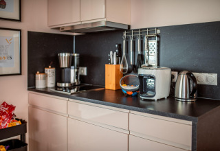 Modern kitchen counter featuring a coffee maker, kettle, air fryer, and utensils on Houseboat am Bärwalder See.