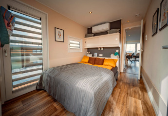 Schlafzimmer auf der Houseboat am Bärwalder See mit Doppelbett, Holzfußboden und moderner Einrichtung.