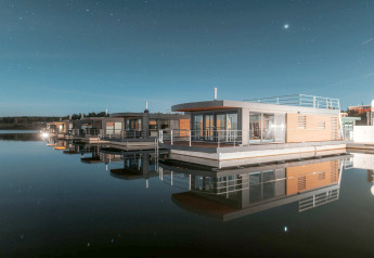Moderne Hausboote auf spiegelglattem Wasser unter einem sternenklaren Nachthimmel am Bärwalder See.