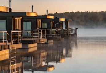 Moderne woonboten bij dageraad op Houseboat am Bärwalder See, weerspiegeld in het kalme water van het meer.