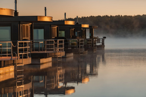Modern houseboats at sunrise on Houseboat am Bärwalder See, reflected in the calm waters of the lake.
