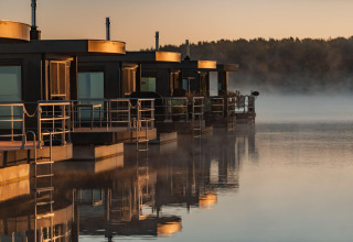 Moderne husbåde ved solopgang på Houseboat am Bärwalder See med spejling i det stille vand.