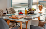 Sfeervol gedekte tafel op Houseboat am Bärwalder See met wijn, kaas, fruit en uitzicht op het meer.