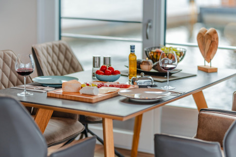 Beautifully set table on Houseboat am Bärwalder See with wine, cheese, fruit and lake view.